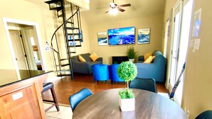 A dining area with a round wooden table, blue chairs, and a small potted plant.