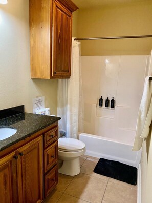 A bathroom with wooden cabinets, a white toilet, a shower with a glass door, and toiletries on the wall.