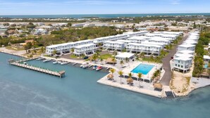 A coastal hotel with multiple white buildings, a swimming pool, and a dock with boats. - Ocean Isles Seaside Oasis (Marathon)