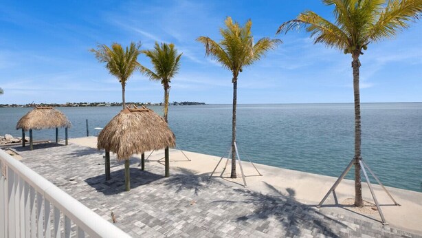 A beachside terrace with palm trees and thatched umbrellas. - Ocean Isles Seaside Oasis (Marathon)