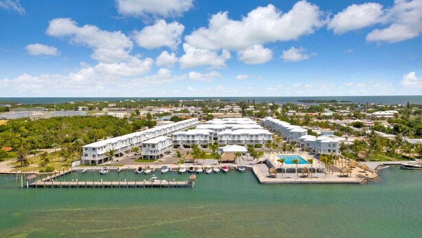 Um resort com vários edifícios, uma marina com barcos e uma área de piscina.