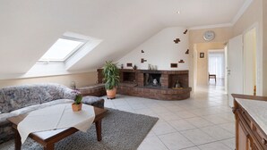 Un salon avec un canapé, une table basse, une cheminée et une lucarne.