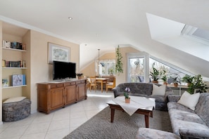A spacious living area with a television, sofa, and dining table.