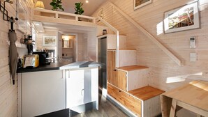 A compact kitchen with white cabinets, a wooden countertop, and a built-in stove. - Tiny Home 'Tiny House Nr 3' with private terrace, Wi-Fi and air conditioning (Schwielowsee)