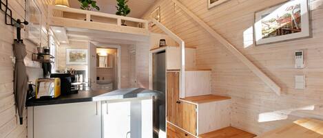 A compact kitchen with white cabinets, a wooden countertop, and a built-in stove.