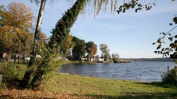 Une vue sur le lac, avec des arbres, un ciel dégagé et une rive lointaine.