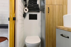 Een kleine badkamer met toilet, een handdoekhouder en een kastje.
