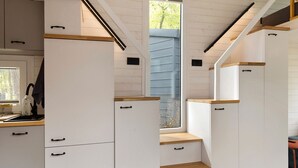 A modern kitchen with white cabinetry, wooden countertops, and a window with a view of the outside.