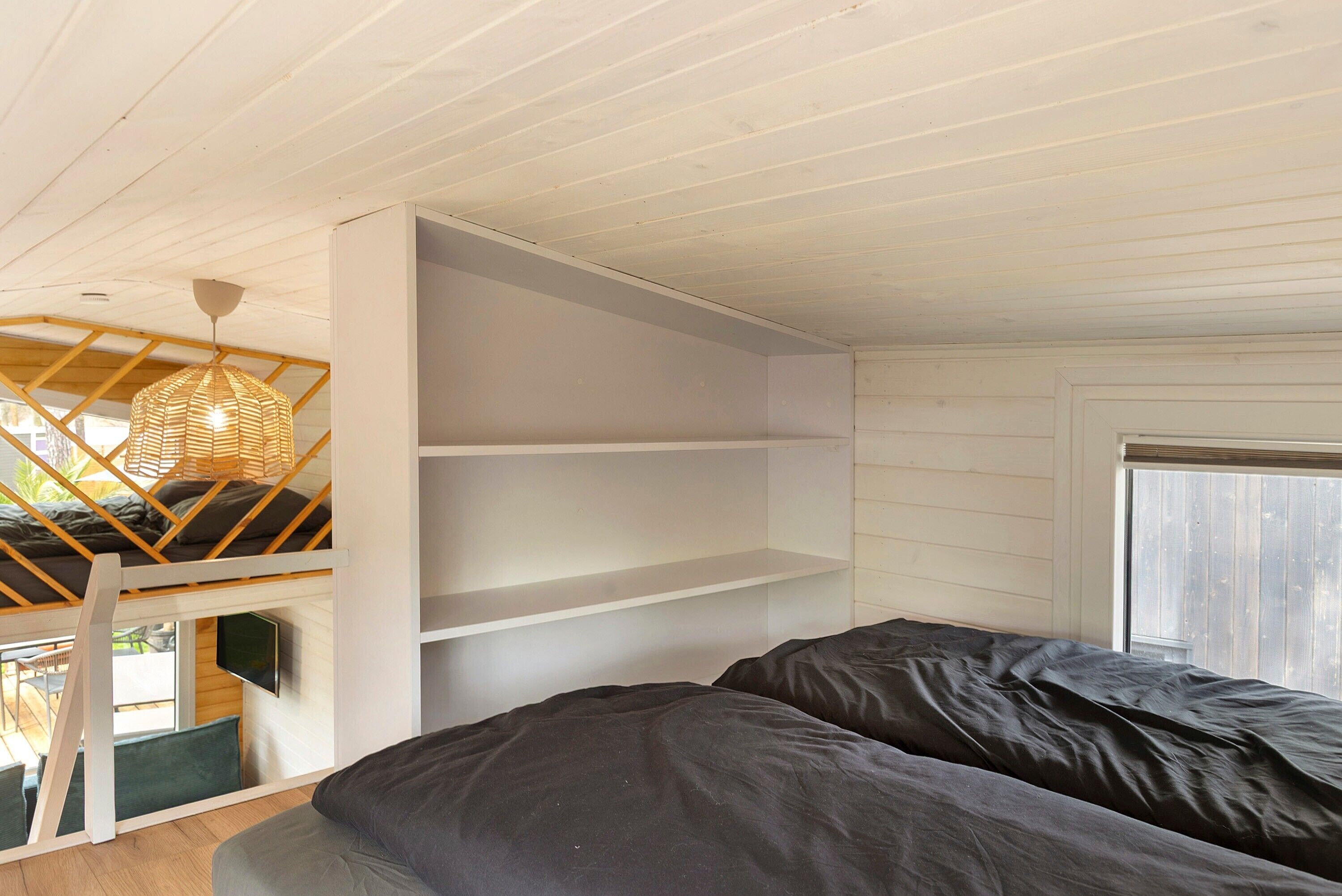 Ein Zimmer mit einem Schlafplatz auf Hochbett und einem Fernseher, sowie einem Fenster.