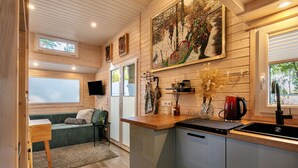 Une cuisine compacte dotée d’un plan de travail en bois, d’un évier et d’un coin repas avec un banc et une table.