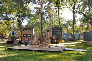 Une terrasse en bois avec des meubles d’extérieur, une petite scène et un bâtiment orné d’une fresque murale.