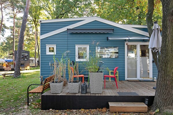Une maison bleue avec une terrasse, des meubles d’extérieur et des plantes en pot.