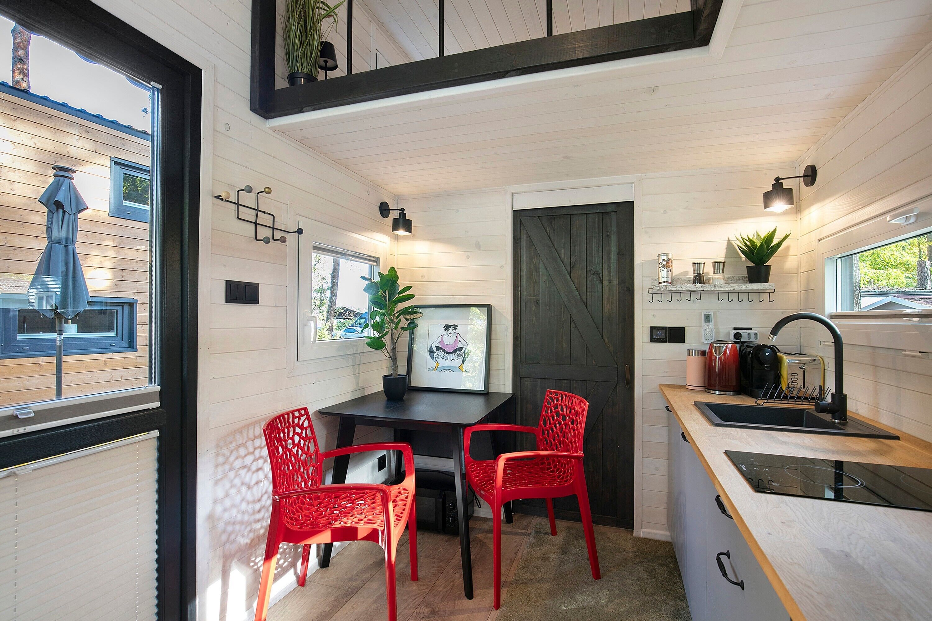 A compact kitchen with a dining area, featuring a table, chairs, a sink, and a window overlooking the outside.