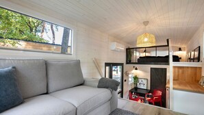 A modern interior with a sofa, a dining area, and a loft space. - Tiny Home 'Tiny House Nr 4' with private terrace, Wi-Fi and air conditioning (Schwielowsee)