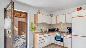 Una cucina con mobili bianchi, un forno a microonde, un fornello e un lavandino.