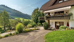 Una casa a due piani con un balcone, immersa nel verde e con vista sulla valle.