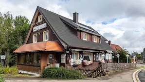 Een klassiek gebouw met een schuin dak, grote ramen en een houten omheining.
