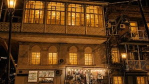 Un edificio histórico con balcón, ventanas amplias y una tienda en la planta baja.