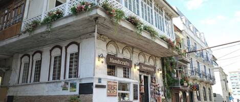 A building with a balcony, signs for 'Handicrafts' and 'Souvenirs', and a street view.