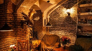 Una habitación acogedora con pared de ladrillo, una silla de madera, una mesa con un jarrón y un sofá.
