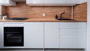 A modern kitchen with white cabinets, a wooden countertop, a gas stove, a sink, and a dishwasher.