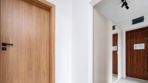 A hallway with wooden doors, white walls, and a tiled floor.