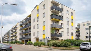Un immeuble d’appartements moderne doté de balcons, une rue et des voitures garées.