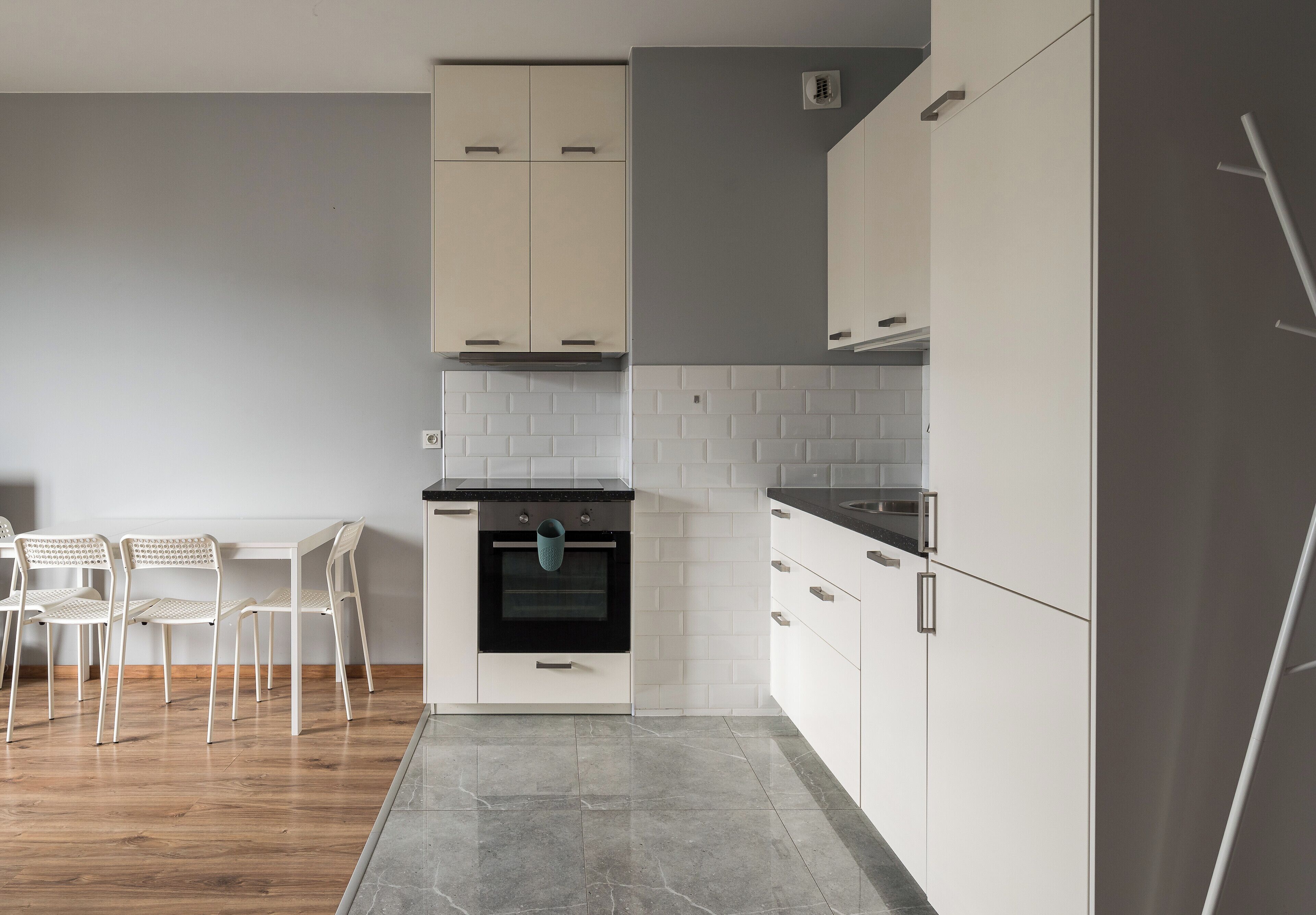A modern kitchen with white cabinets, a black oven, and a grey refrigerator.