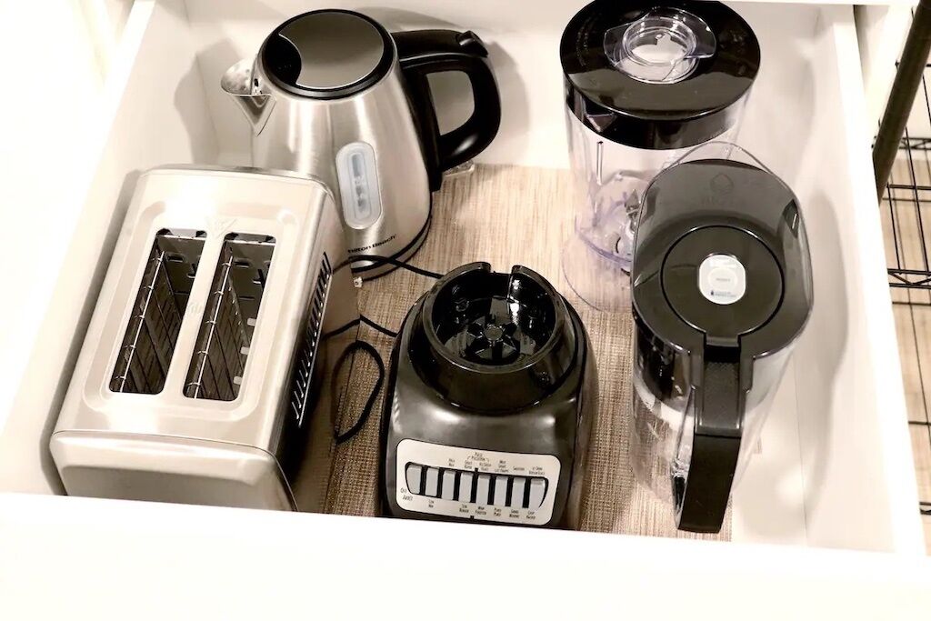 A drawer containing a toaster, a kettle, a blender, and a coffee maker.