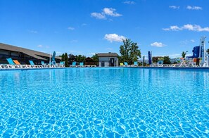 A swimming pool with lounge chairs and a small building in the background.