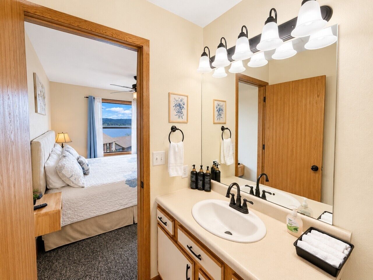 A hotel room with a bed, a bathroom with a sink and mirror, and a view of the mountains.