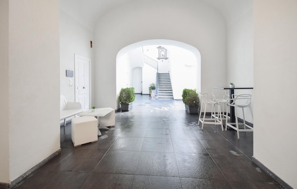 A hallway with a white door, a white bench, a small table, and a staircase leading to an upper level. - 1 bedroom cozy apartment in Torre del Greco (Torre del Greco)