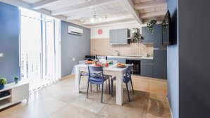 A modern kitchen with a dining area, featuring a white table, blue chairs, and a tiled backsplash.