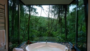 A modern bathroom with a large bathtub, candles, and a bottle of champagne. - Rainforest Canopy Bungalow @ Crystal Creek Rainforest Retreat  (Upper Crystal Creek)