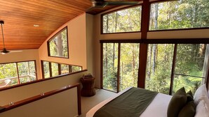A bedroom with a large bed, multiple windows, and a ceiling fan. - Rainforest Canopy Bungalow @ Crystal Creek Rainforest Retreat  (Upper Crystal Creek)