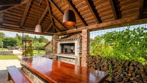 An outdoor bar area with a stone fireplace, wooden beams, and a stone bench. - Villa Nina (Istria - Buje) (Buje)
