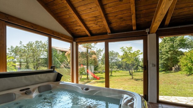 A hot tub with a wooden ceiling and large windows overlooking a grassy area with trees and a slide. - Villa Nina (Istria - Buje) (Buje)