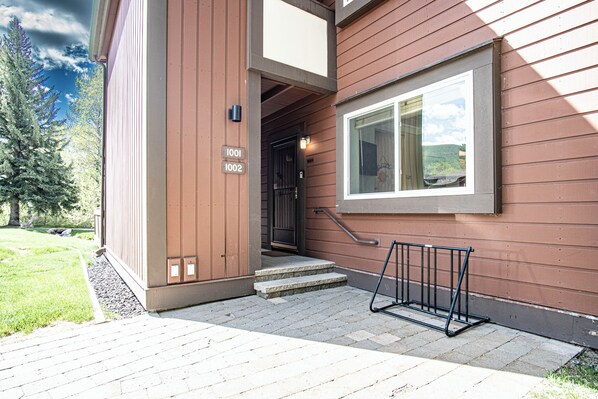 A building entrance with a set of steps leading up to a door, a mailbox, and a window with a view of the landscape.