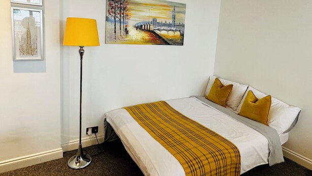 A hotel room with a bed, a lamp, and two paintings on the wall.