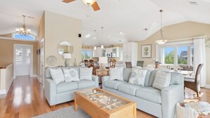 A spacious living room with a high ceiling, a ceiling fan, and a dining area with a kitchen in the background. - Top of the Hill: Private Pool, Hot Tub & Sun Deck (Corolla)