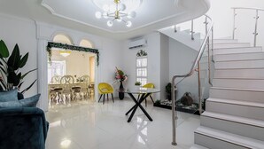 Ein modernes Interieur mit Treppe, Essbereich mit gelben Stühlen und einer Chandelüster.