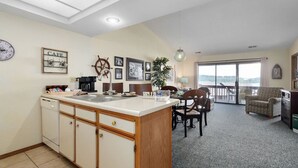 A kitchen with a central island, a dining area with chairs, a clock, and a 'CAFE' sign on the wall. - Captain`s Quarters at Kimberling Crossing (Kimberling City)