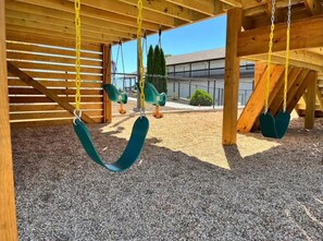 Un parque infantil con columpios y una zona cubierta.