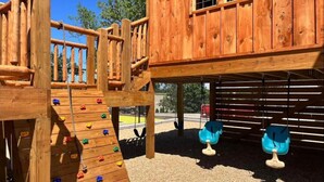 A wooden play structure with a climbing wall and swings. - Captain`s Quarters at Kimberling Crossing (Kimberling City)