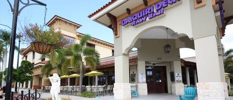 The exterior of Daiquiri Raw Bar with outdoor seating and a statue in the foreground.