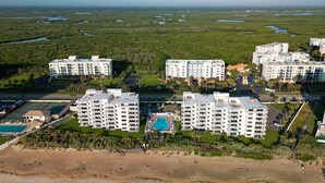 Ein Strandhotel mit mehreren Gebäuden, einem Swimmingpool und einem Strandabschnitt.