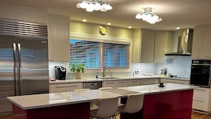 A modern kitchen with a central island, stainless steel appliances, and a seating area with chairs. - Murfreesboro Mid-Century Modern with AC, WiFi (Murfreesboro)