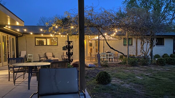 An outdoor patio area with a dining table and chairs, surrounded by a brick wall and trees. - Murfreesboro Mid-Century Modern with AC, WiFi (Murfreesboro)