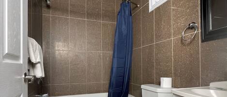 A bathroom with a bathtub, toilet, and a shower curtain.