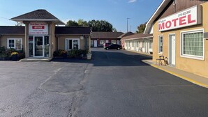 A motel with a welcoming sign, a visible office, and a parking area. - WAYFARE MOTEL (Guelph)